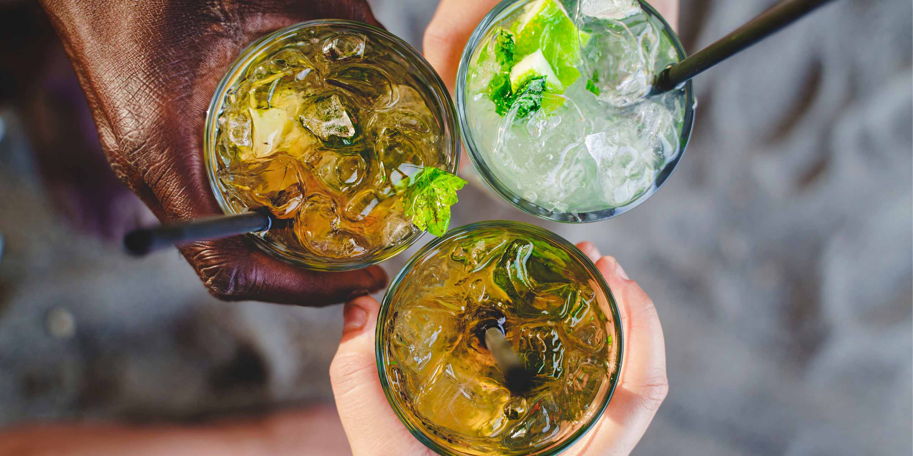 Three people holding their cocktails together