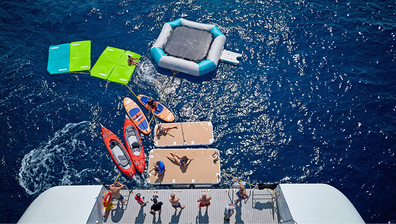 aerial view of a marina platform at the rear of a superyacht with a trampoline, stand up paddle boards and sea kayaks in the water