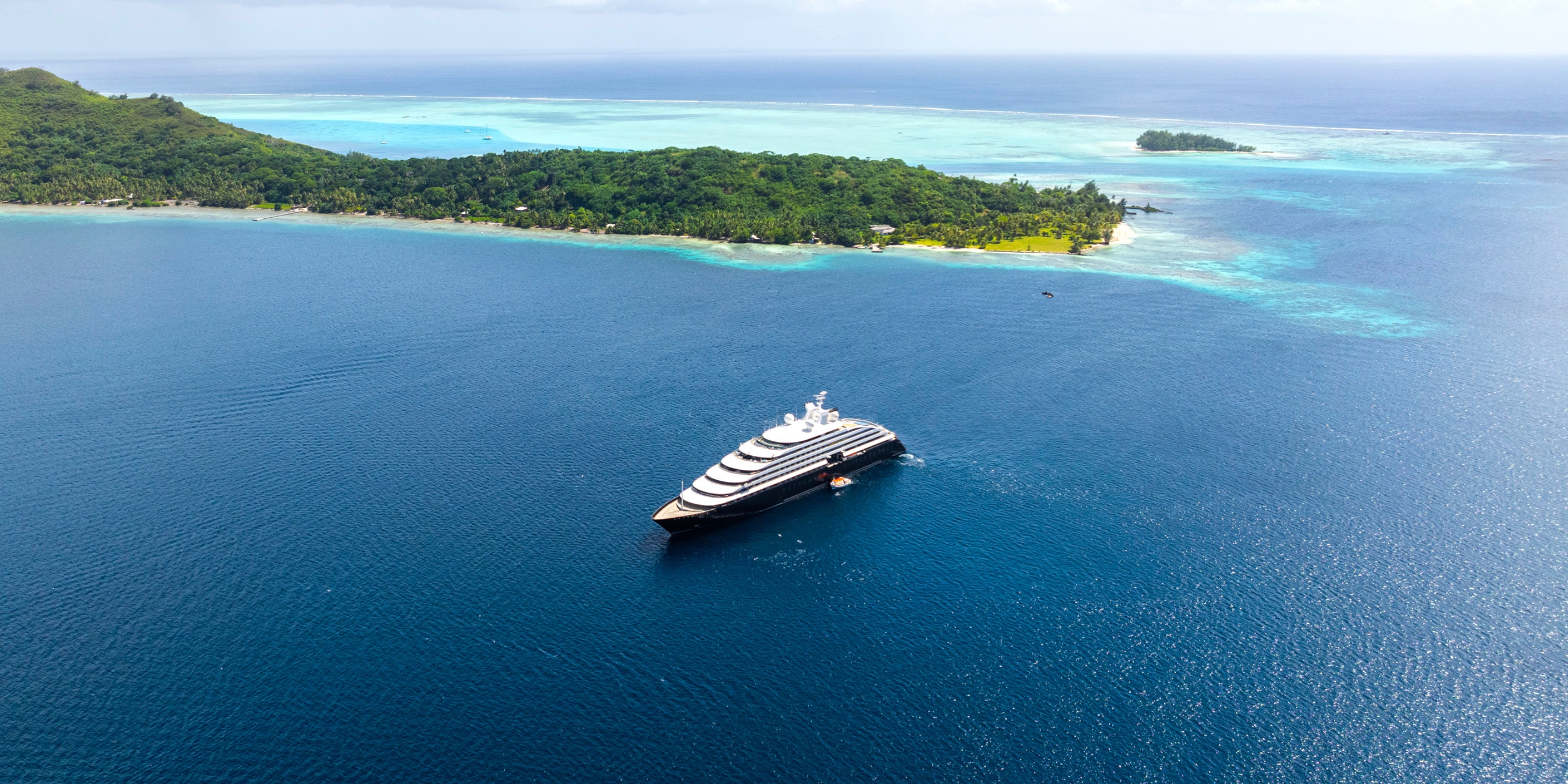 luxury ocean cruise discovery yacht sailing in the blue waters of bora bora next to an island cove
