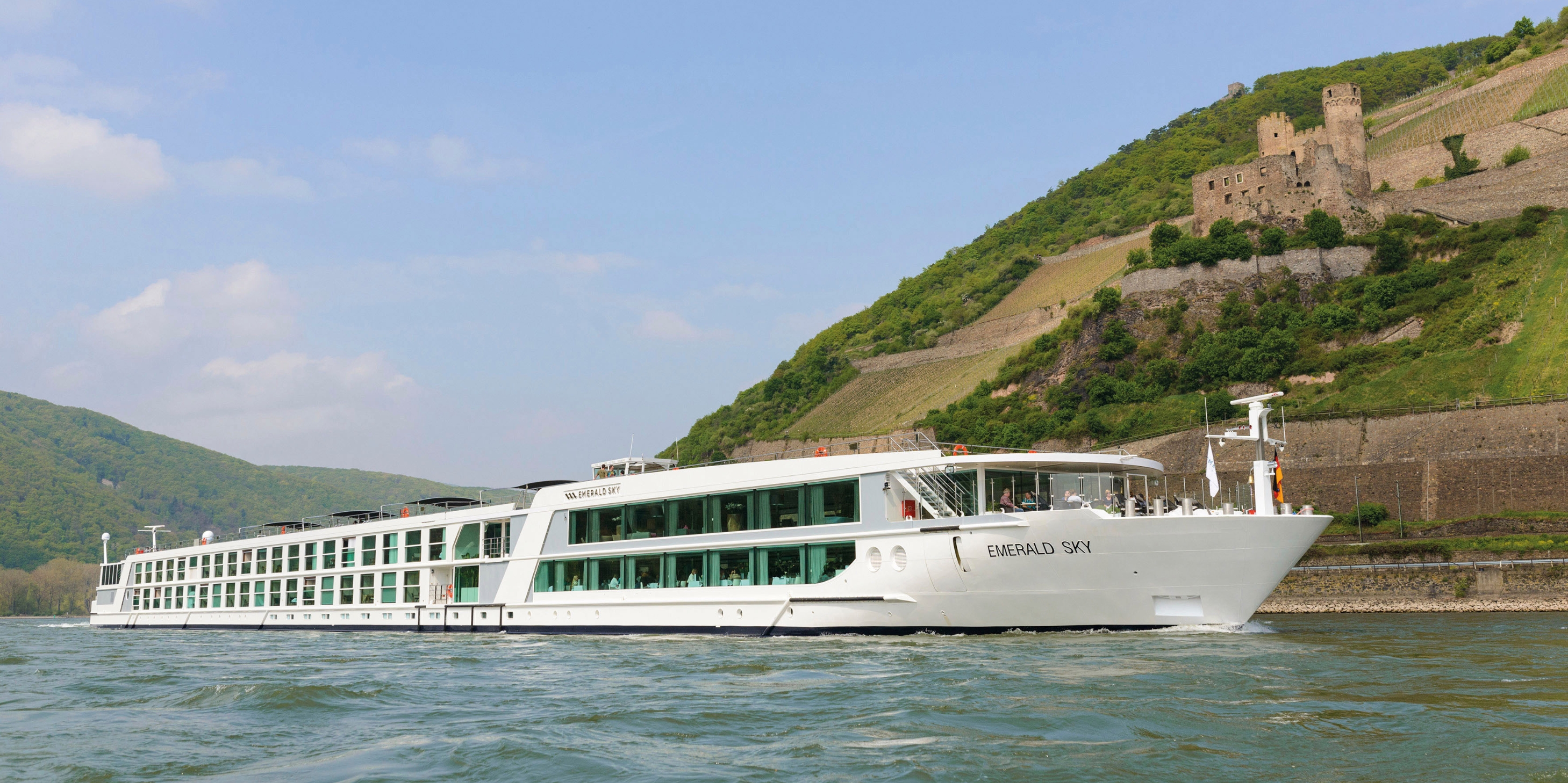 Luxury river cruise ship sailing next to a cliff with a castle on it
