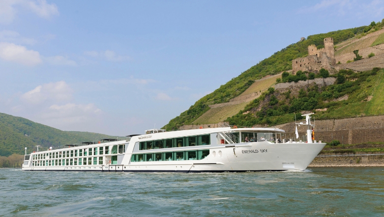 Luxury river cruise ship sailing next to a cliff with a castle on it