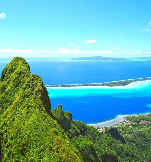 The peak of a mountain overlooking the bright blue waters surrounding an island in Polynesia