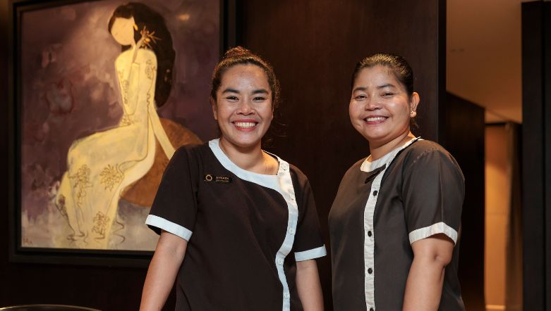 Two ladies standing in front of a piece of artwork wearing black and white tops