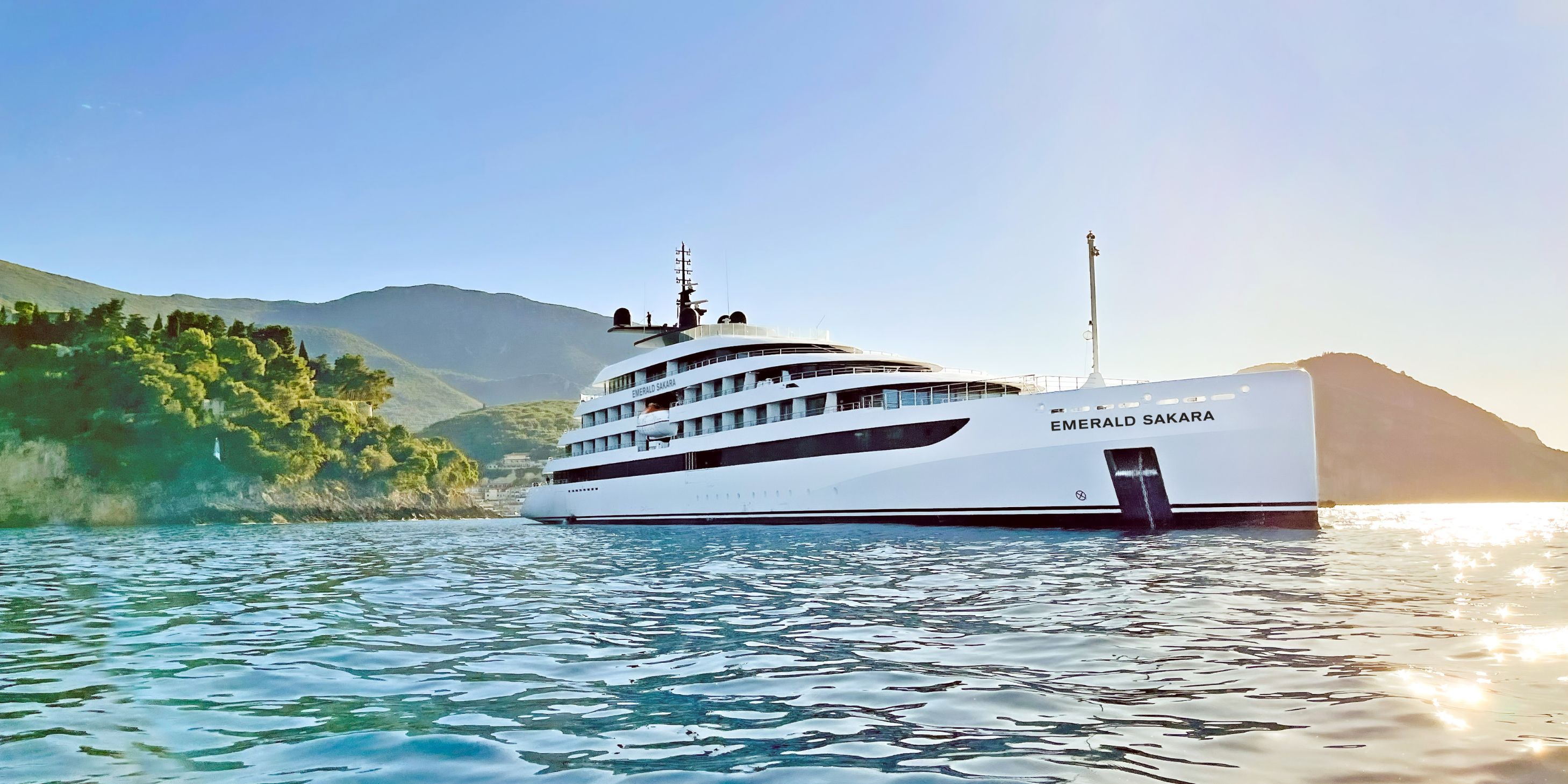 Luxury yacht in the ocean off the coast of Croatia, with lush green foliage in the background under blue skies.