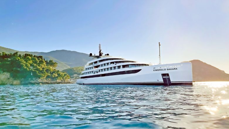 Luxury yacht in the ocean off the coast of Croatia, with lush green foliage in the background under blue skies.