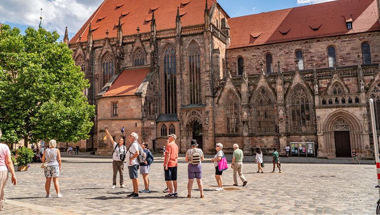 Group of tourists walking around a town square in Nuremburg following a tour guide